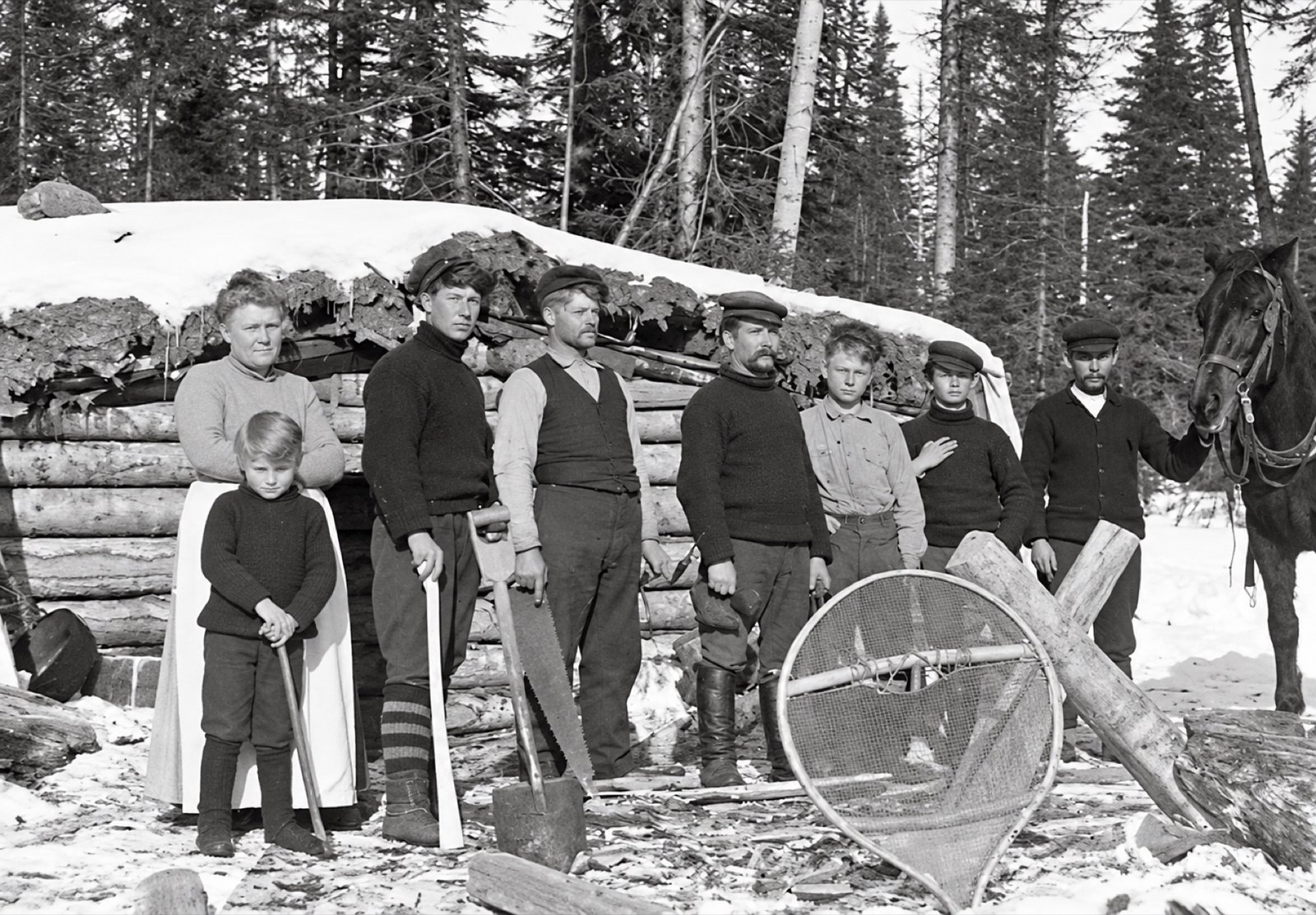 Groupe devant un abri de bois en forêt, photographie restaurée